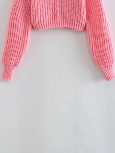 Dettaglio della trama in maglia a coste rosa su un maglione corto girocollo con polsini