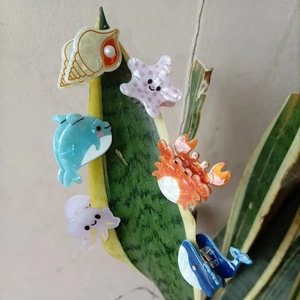 Close-up of 6-piece colorful marine animal hair clips set displayed on green leaf