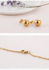 Detailed view of gold stainless steel ball earrings and chain necklace with lobster clasp