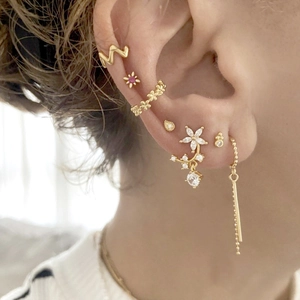 Elegant gold flower earrings set with red zircon and tassels worn by a model