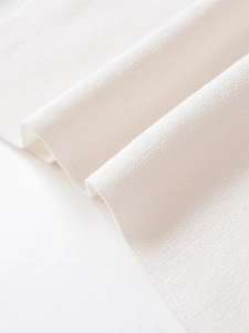 Makroaufnahme von reinweißem Strickstoff mit feiner Textur und weichem Fall