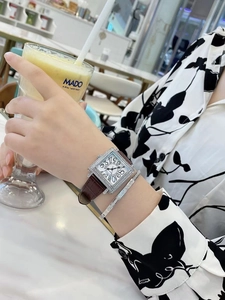 Detalle de reloj cuadrado con diamantes y pulsera de plata a juego en la muñeca femenina