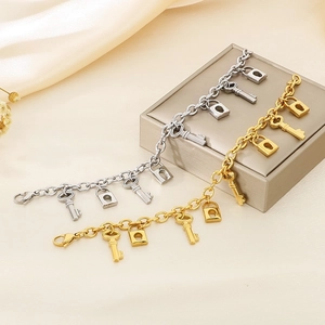 Detail of gold and silver key and lock pendants on high-polished stainless steel bracelets