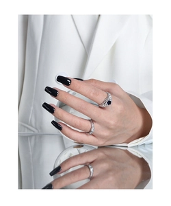 Detailed view of vintage hollow ring with blue gemstone and pavé band on model's hand