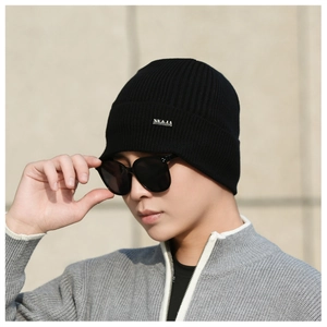 Detail of black ribbed knit beanie featuring a metallic NY&JA logo tag on the folded cuff