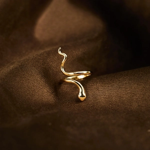 Macro shot of adjustable gold snake ring with a polished metallic finish on textured fabric