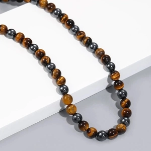 Men's beaded necklace with black hematite and tiger eye stones on white geometric stand