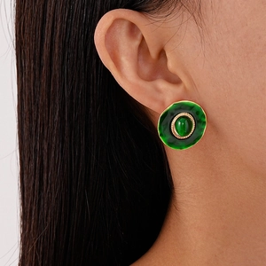 Gros plan d'une boucle d'oreille rétro en résine vert émeraude avec bord doré sur un mannequin