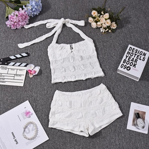 Flat lay of white textured halter top and shorts set with stylish lifestyle props