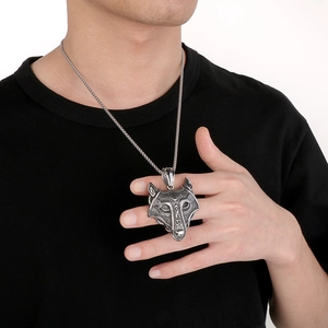 Close-up of vintage silver wolf head pendant with Celtic relief on male model