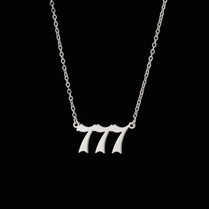 Macro detail of silver gothic number 777 pendant on delicate stainless steel chain