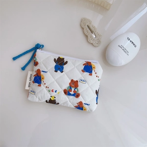 Détail macro d'une pochette en coton matelassé avec imprimé ours et zip bleu