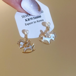 Detail shot of gold-plated rocking horse earrings with pearls and sparkling zircons