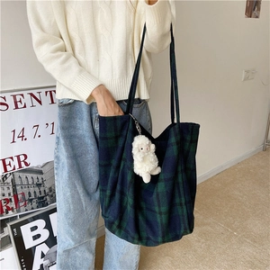 Detailed side view of blue and green plaid tote bag with cute plush sheep keychain accessory