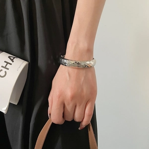 Détail d'un bracelet jonc argenté avec texture taillée en diamant et éclat métallique