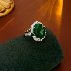 Close-up of green oval zircon ring with micro-pave setting on a velvet holder