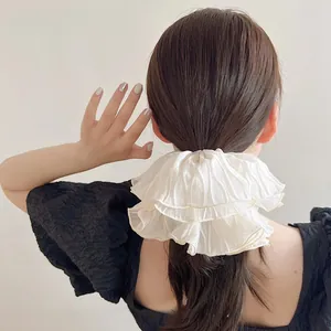 Close-up of oversized cream pleated chiffon scrunchie on a ponytail hair tie