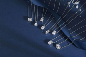 Détail de colliers en argent avec diverses tailles de pierres sur fond bleu luxe