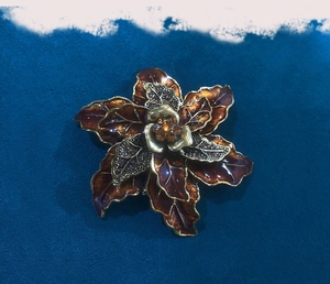 Macro view of vintage floral brooch with brown enamel petals and amber crystal center