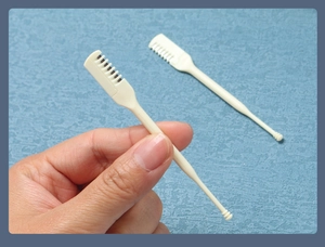 Detail of dual-ended nose hair trimmer with safety comb teeth and beige plastic handle