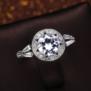 Macro shot of halo engagement ring with round center stone and baguette side diamonds