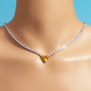 Close-up of zircon heart necklace with yellow gemstone and silver chain on mannequin