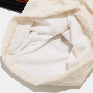Detail of off-white knitted beanie showing waffle texture and soft white inner lining