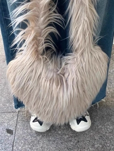 Street style shot of heart shaped faux fur handbag paired with denim and sneakers