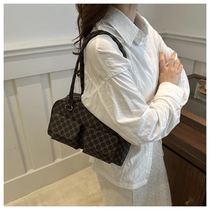 Detail view of retro brown monogram shoulder bag with dual front flap pockets on a model