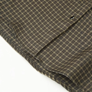 Primo piano di camicia a quadri marrone con trama del tessuto e bottoni neri su sfondo bianco