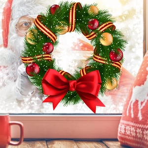 Détail d'une couronne de Noël avec baies rouges et boules dorées sur une fenêtre givrée