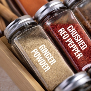 Detail of glass spice jars with metal lids and English labels in a wooden box