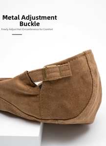 Detail of the bronze metal adjustment buckle on a brown suede newsboy cap for custom fit