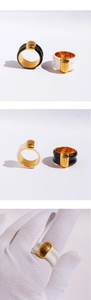 Detail of wide textured gold band rings with black and white enamel finishes