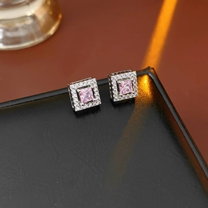 Macro shot of silver square stud earrings featuring pink zircon center and halo diamonds