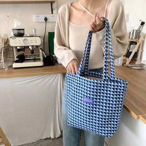Detail of blue and white woven tote bag with a purple label in a cafe setting
