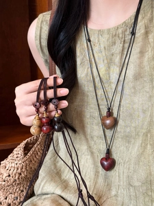 Detail of wooden heart and gourd pendants on woven rope necklaces with vintage ethnic style