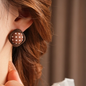Close-up of retro brown polka dot fabric button earring worn on a model's ear