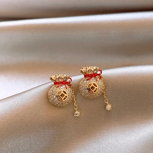 Vue macro de boucles d'oreilles sac de chance doré avec zircon blanc et rouge