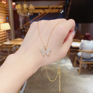 Gros plan d'un collier pendentif papillon doré avec zircons pavés et chaîne ajustable