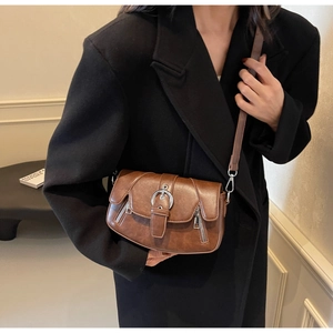 Detail of vintage dark brown saddle bag featuring metal buckle and side zipper accents