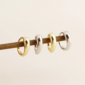 Detailed view of silver and gold teardrop earrings hanging on wood showing S925 stamps