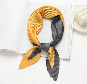 Detailed close-up of yellow and dark gray pleated silk scarf with fine accordion texture