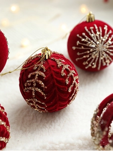Close-up of red velvet Christmas balls with gold sequins and leaf embroidery patterns
