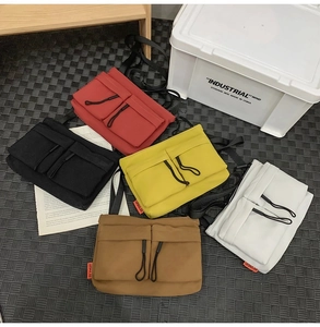 Flat lay of nylon messenger bags in five colors with dual pockets and drawstring zippers