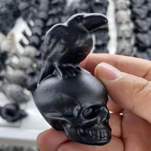 Close-up of a matte black raven skull resin carving held by hand showing fine details