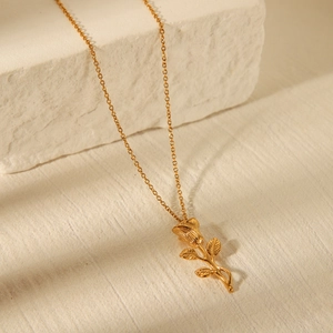 Elegant gold stainless steel rose pendant necklace on a minimalist stone background