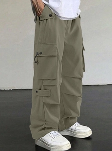 Detail of olive green tactical cargo pants showing large side pockets and drawstring hem