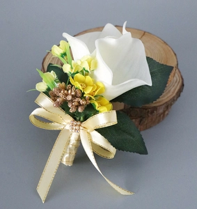 Detail of white calla lily boutonniere with golden beads and champagne ribbon on wood