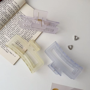 Flat lay of colorful matte acrylic hair claws and silver heart earrings on a book